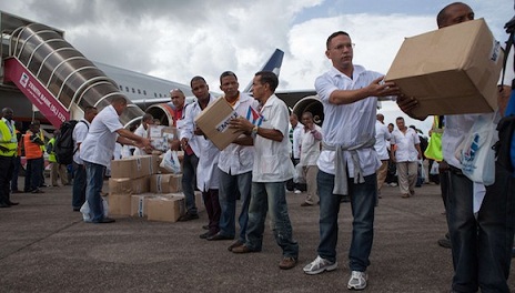 Los primeros miembros de un equipo de 165 médicos cubanos y trabajadores de la salud descargan ellos mismos las cajas de medicamentos y material médico de un avión a su llegada al aeropuerto de Freetown para ayudar a la lucha contra el Ébola en Sierra Leona, el 2 de octubre de 2014. 